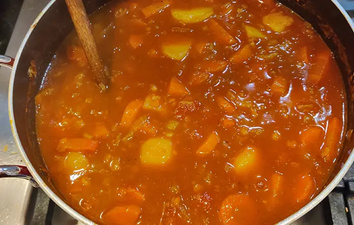 The late stages of the Barley and Vegetable Soup recipe cooking in a red saucepan